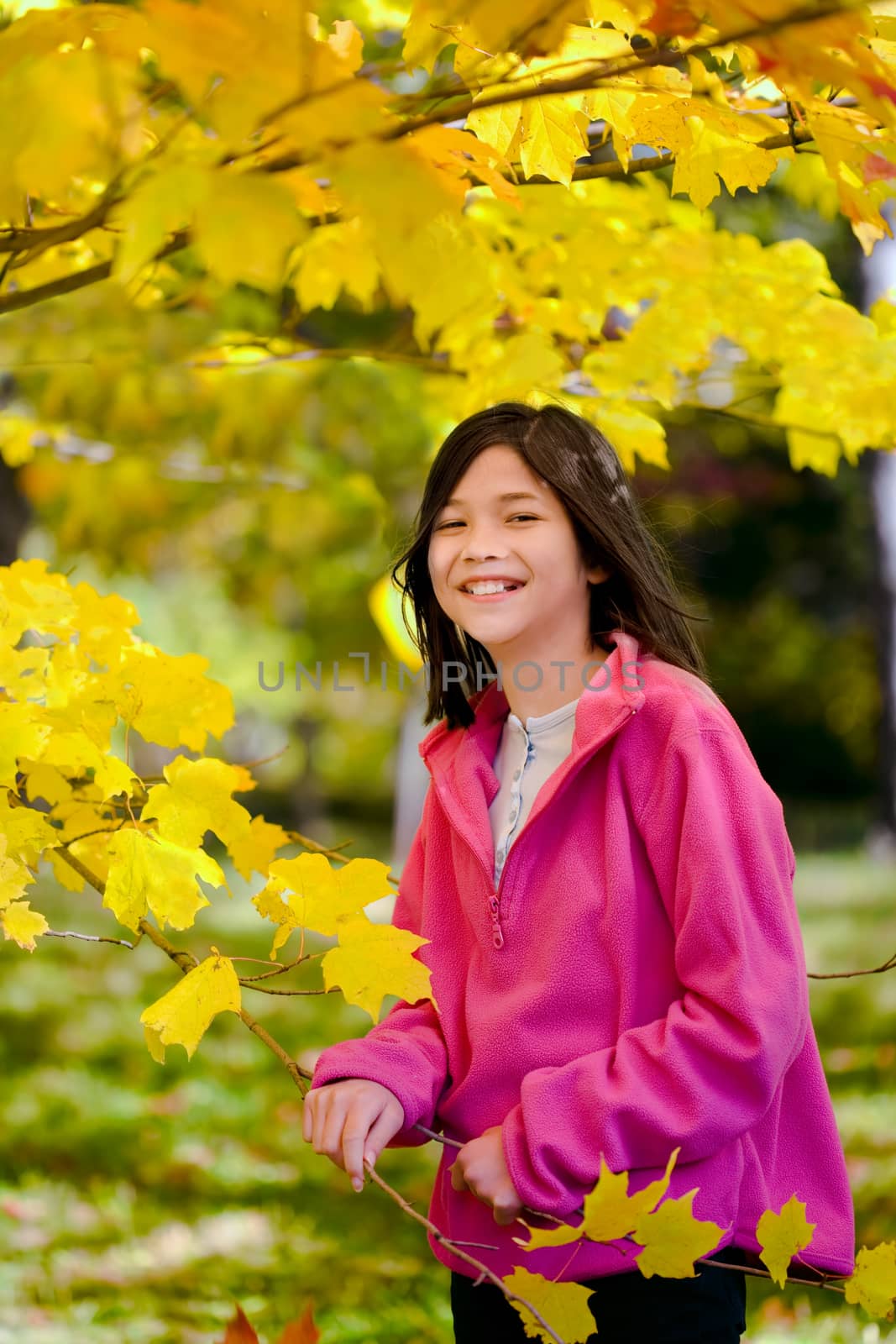 Little biracial asian girl standing amongst bright autumn leaves