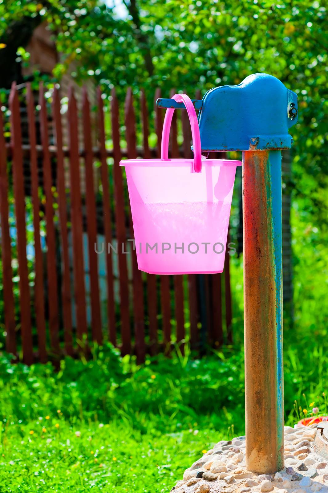 pink plastic bucket and rural well