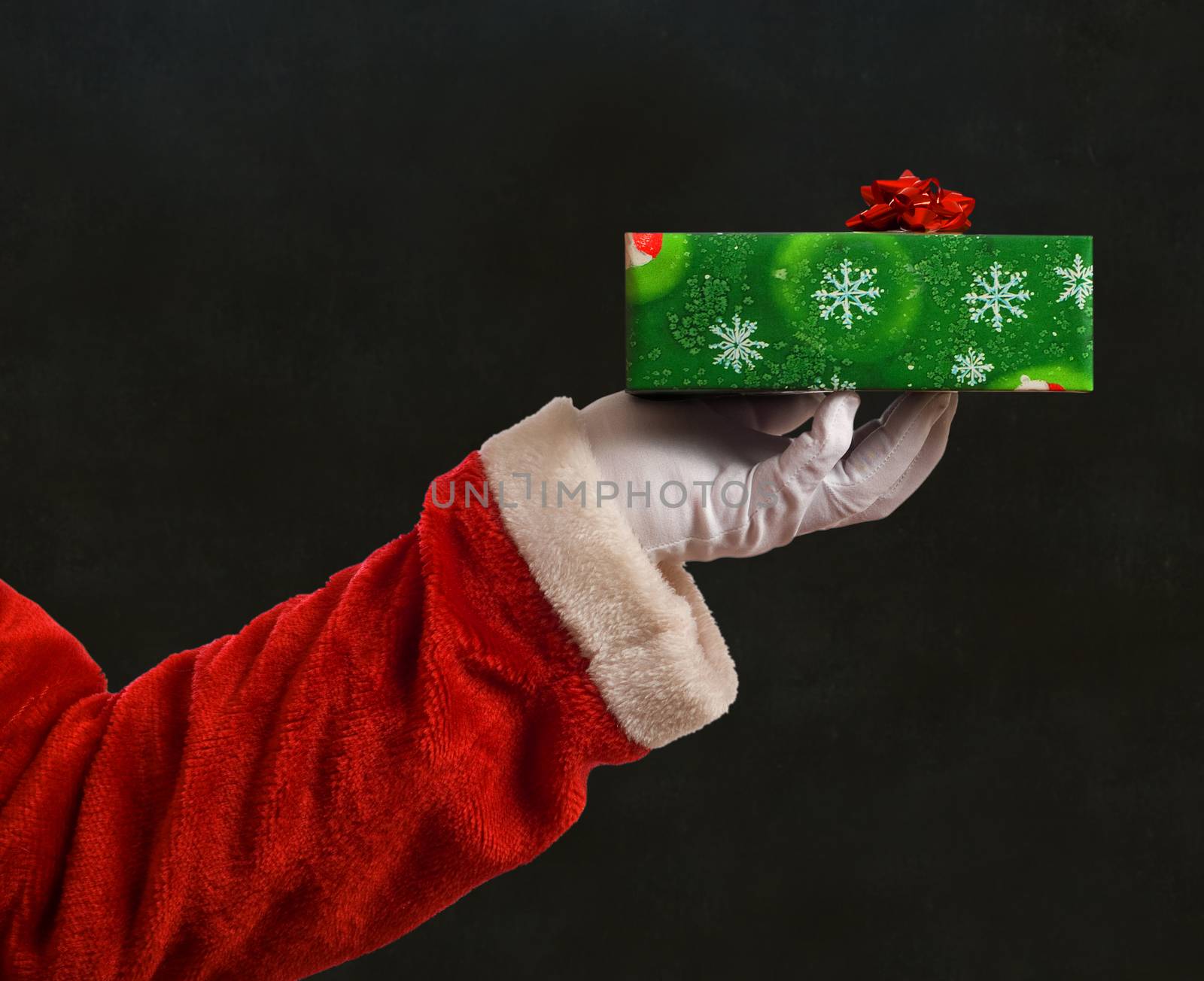 Santa Father Christmas hand with wrapping paper present and red star ribbon decoration on blackboard background