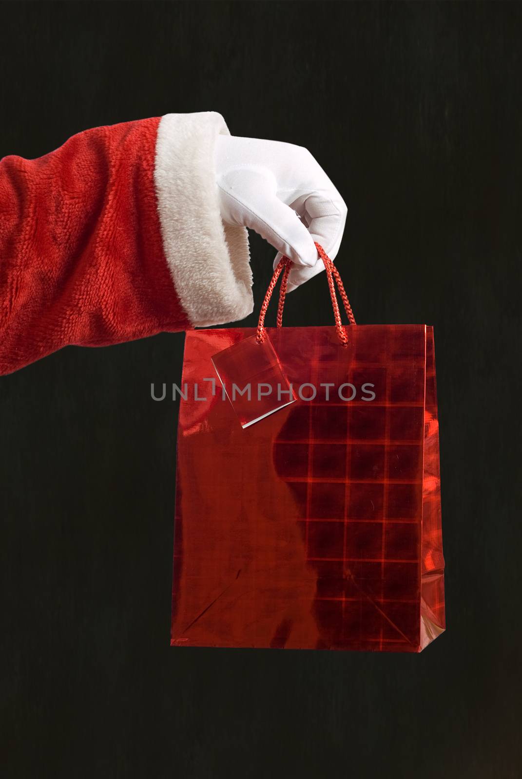 Father Christmas hand holding a red present on blackboard background