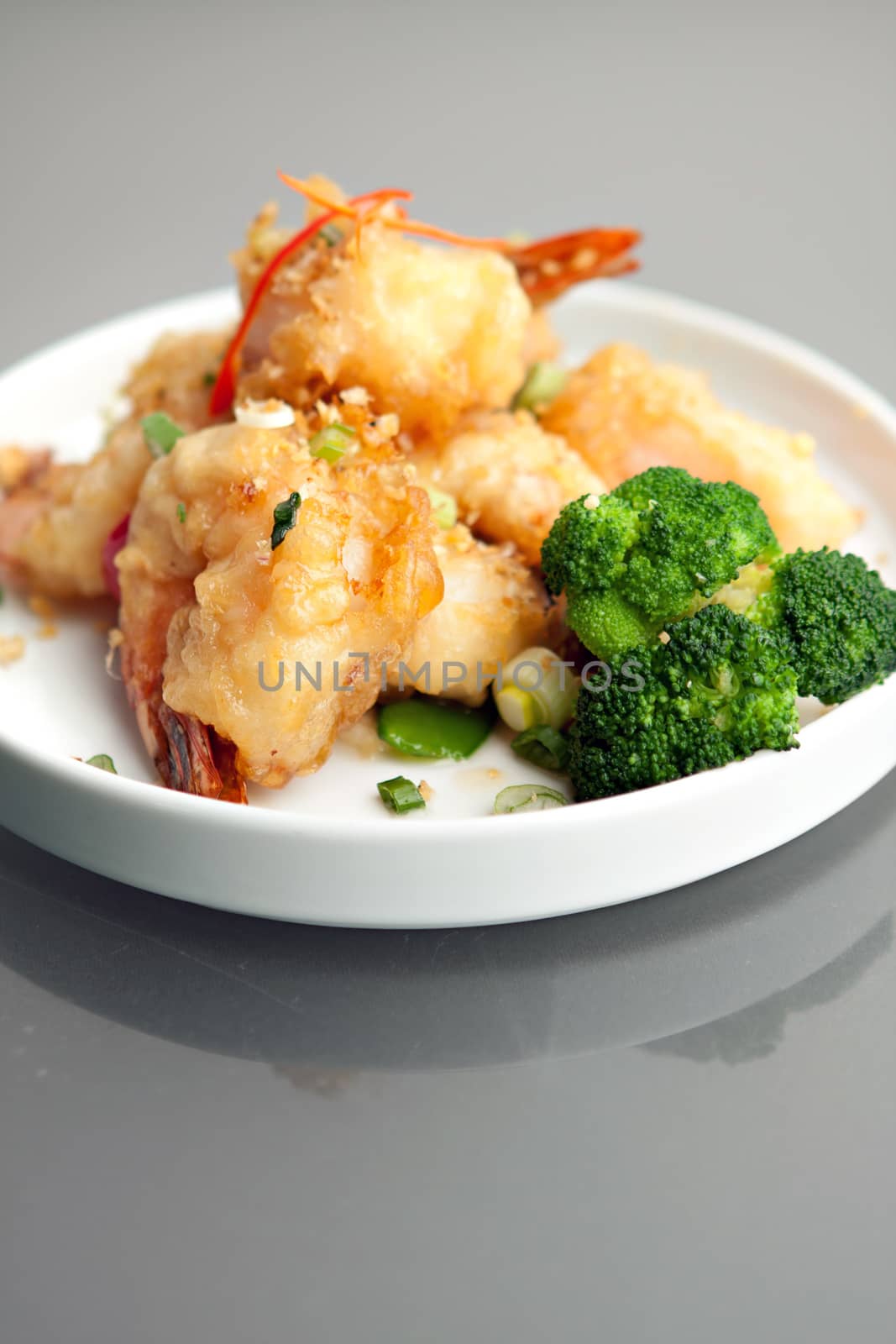 Fried Thai style honey shrimp dish presented beautifully on a round white plate.