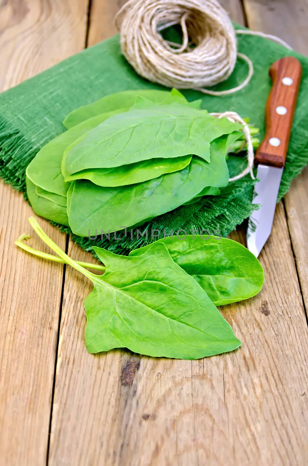 Green spinach, knife, twine, napkin on a wooden board