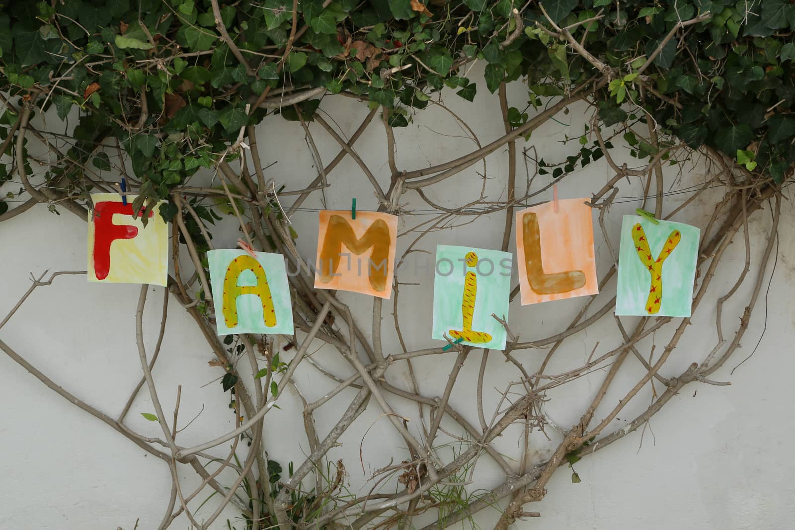 Word "FAMILY" painted on the paper A4 format and attached to the branches of the tree