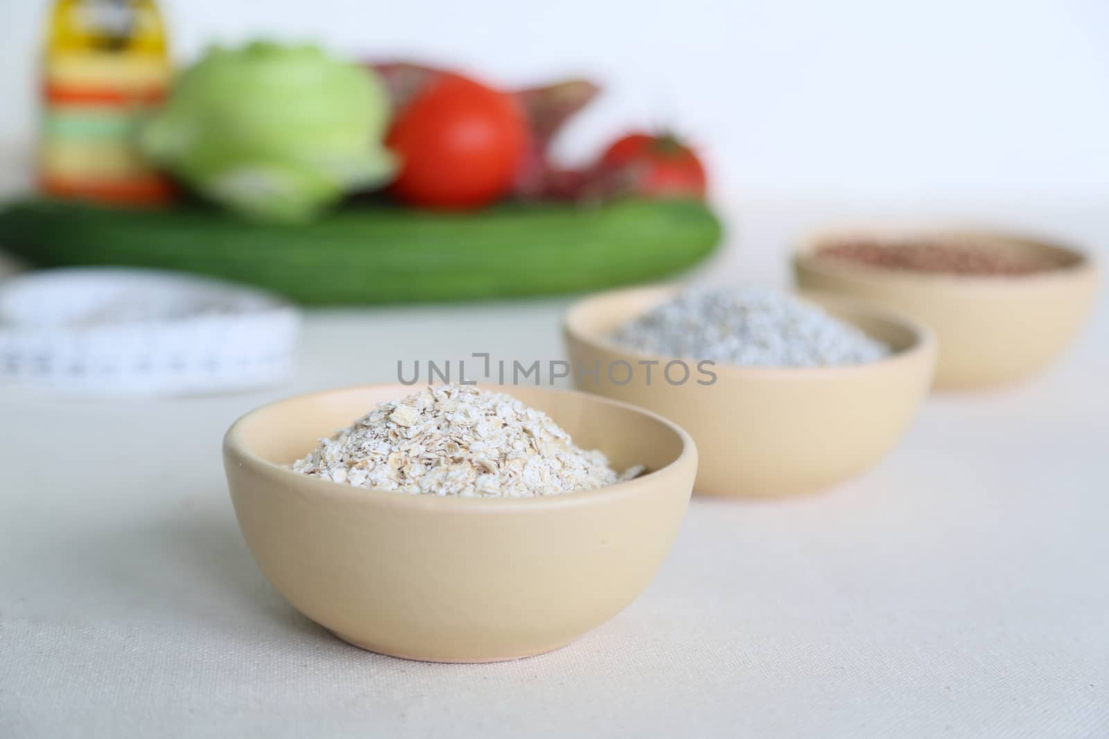 Flakes of oat cereal in the clay salad dish with vegetables in the background