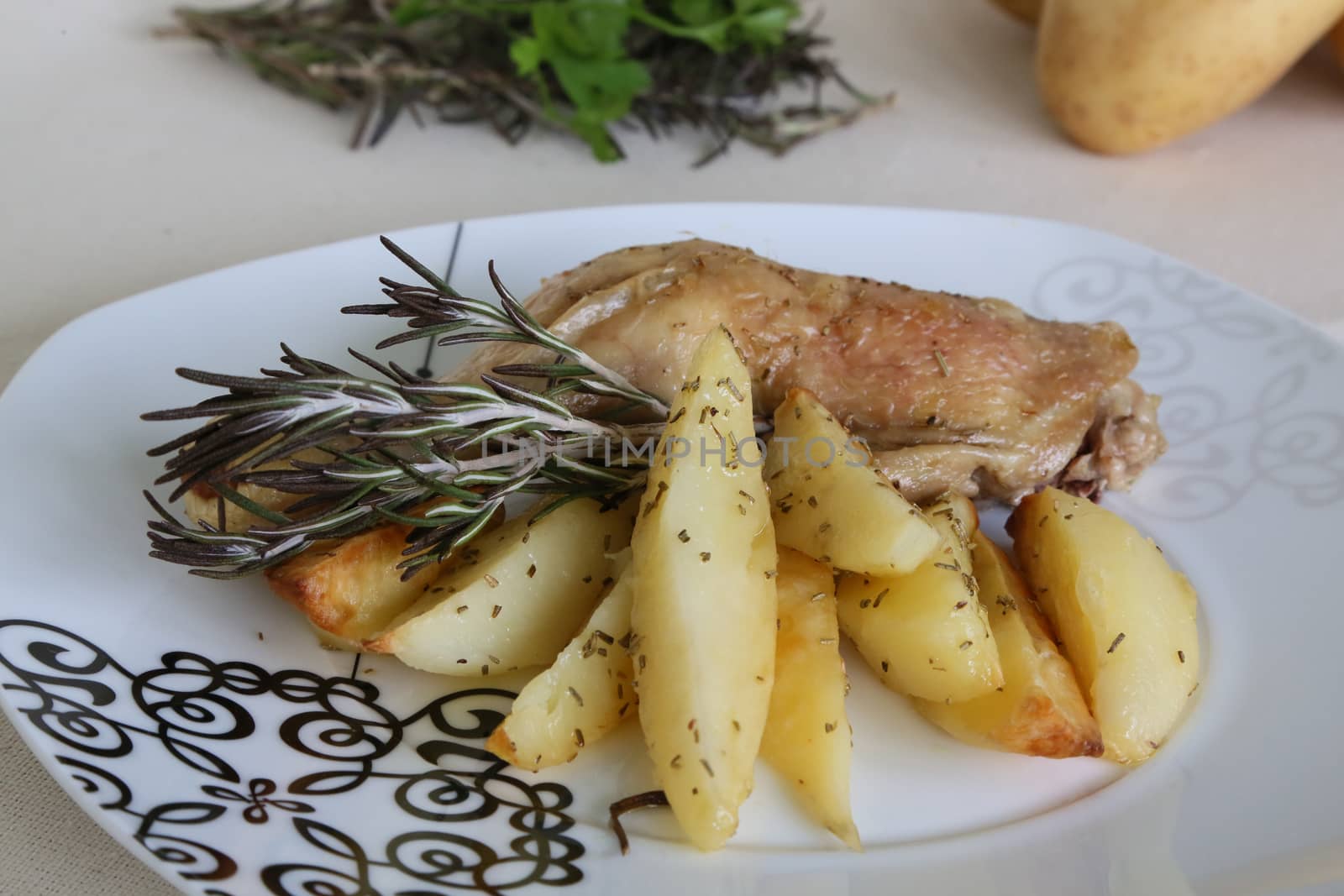 A plate of backed potatoes and chicken with rosemary