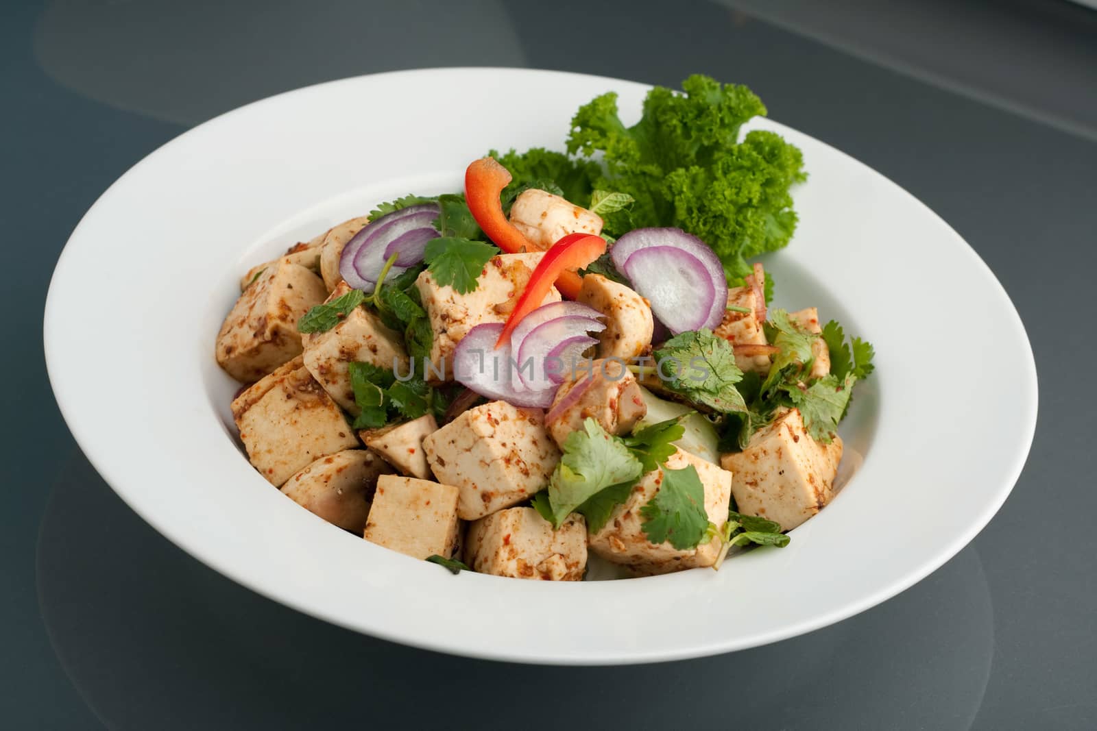 Fresh Thai food stir fry with tofu in a white dish.