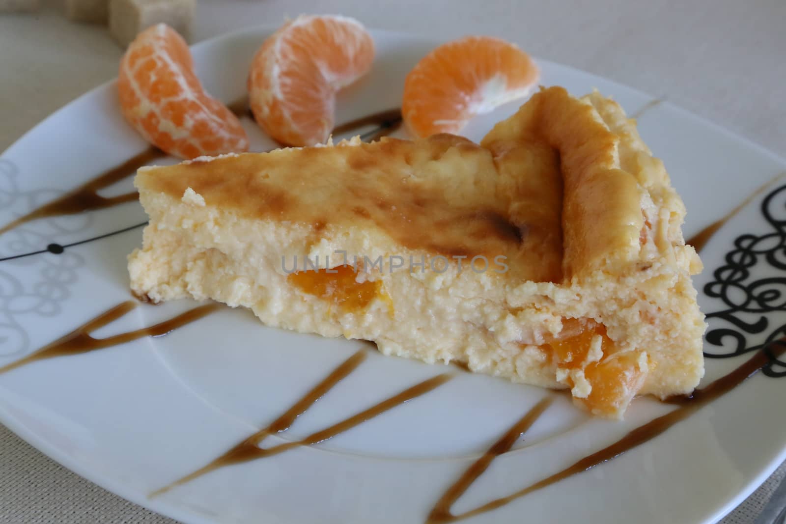 Cheese cake baked from italian ricotta,eggs,sugar,tangerines. The plate is decorated with three cantles of tangerines and caramel toppings
