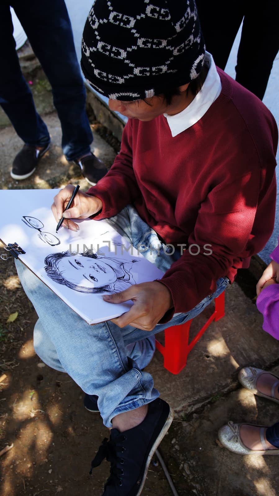 DA LAT, VIET NAM- DEC 27:Pavement artist portray with pencil on white paper for little girl in Dalat, Viet Nam on Dec 27, 2013