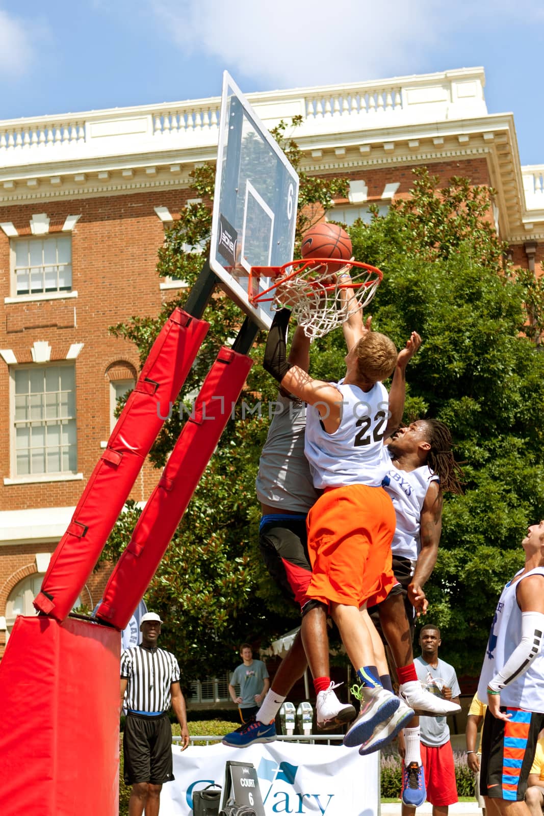 Athens, GA, USA - August 24, 2013:  Three men fight for the ball above the rim, in a 3-on-3 basketball tournament held on the streets of downtown Athens.