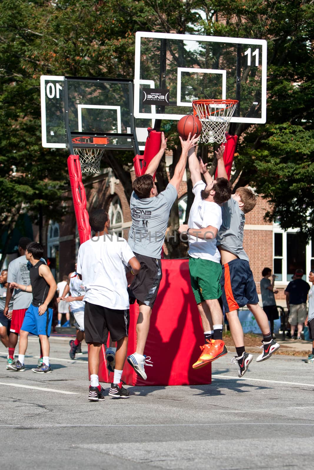 Athens, GA, USA - August 24, 2013:  Three men jump battling for the ball in a 3-on-3 basketball tournament held on the streets of downtown Athens.