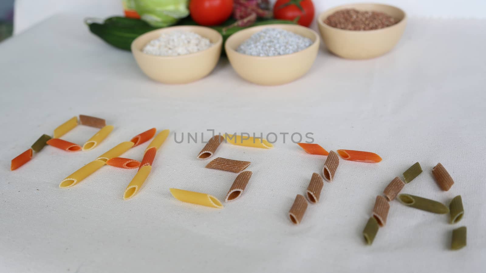 Word PASTA with vegetables and cereals in the background by tolikoff_photography