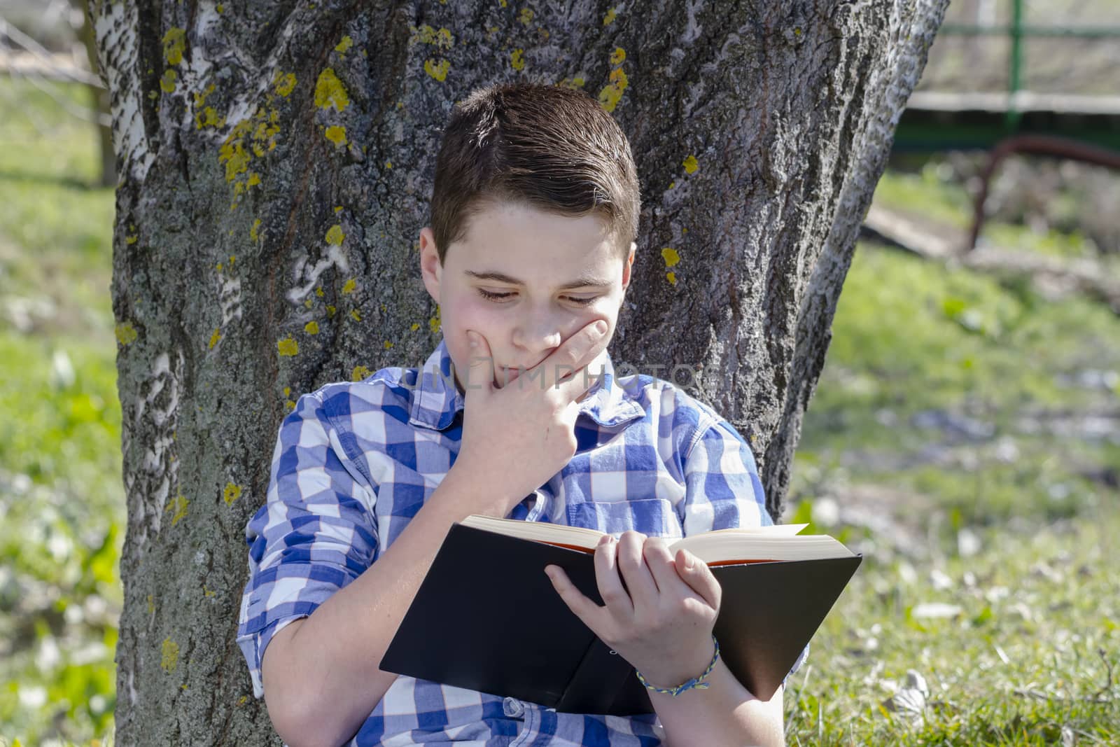 Young boy reading a book in the woods with shallow depth of field and copy space