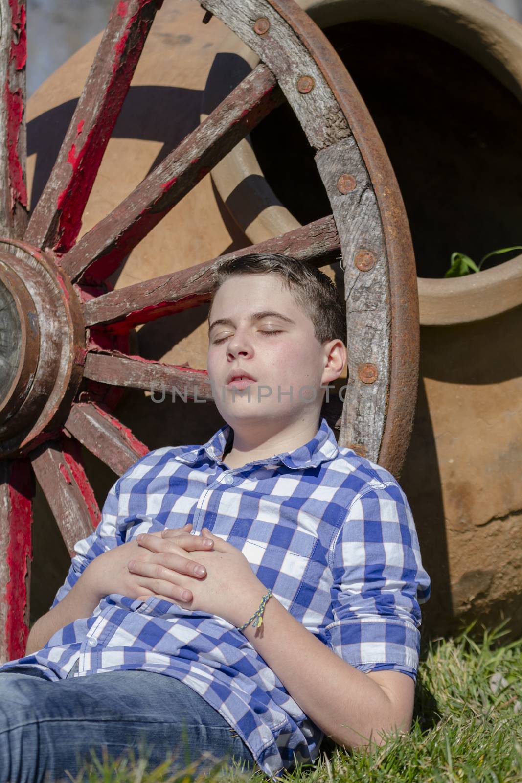 young cowboy lying beside a wagon wheel by FernandoCortes