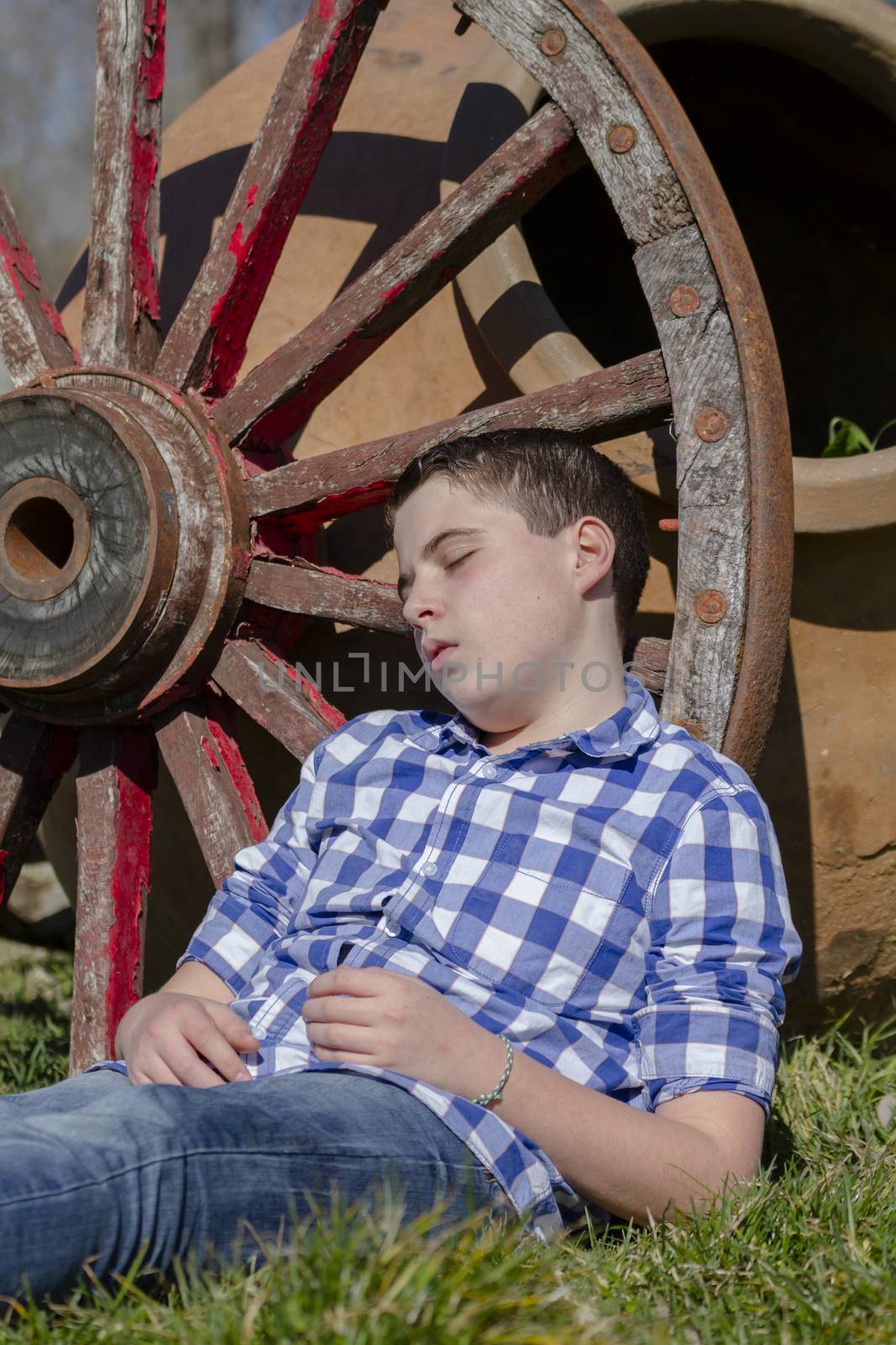 young cowboy lying beside a wagon wheel by FernandoCortes