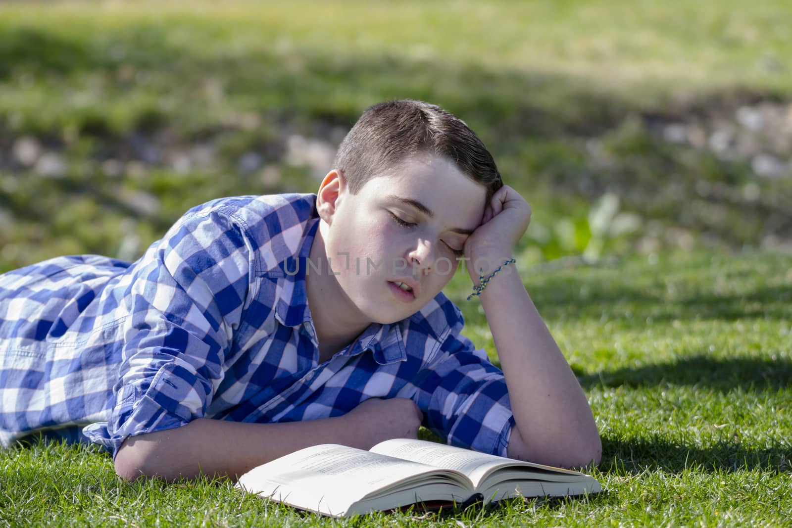 Young boy reading a book in the woods with shallow depth of field and copy space