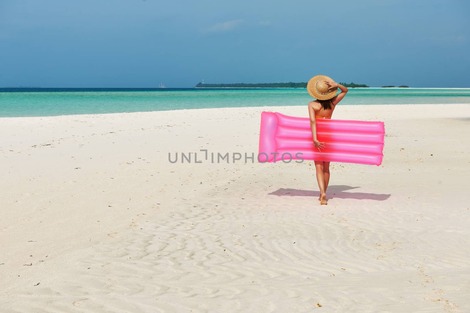 Woman with pink inflatable raft walking at the beach