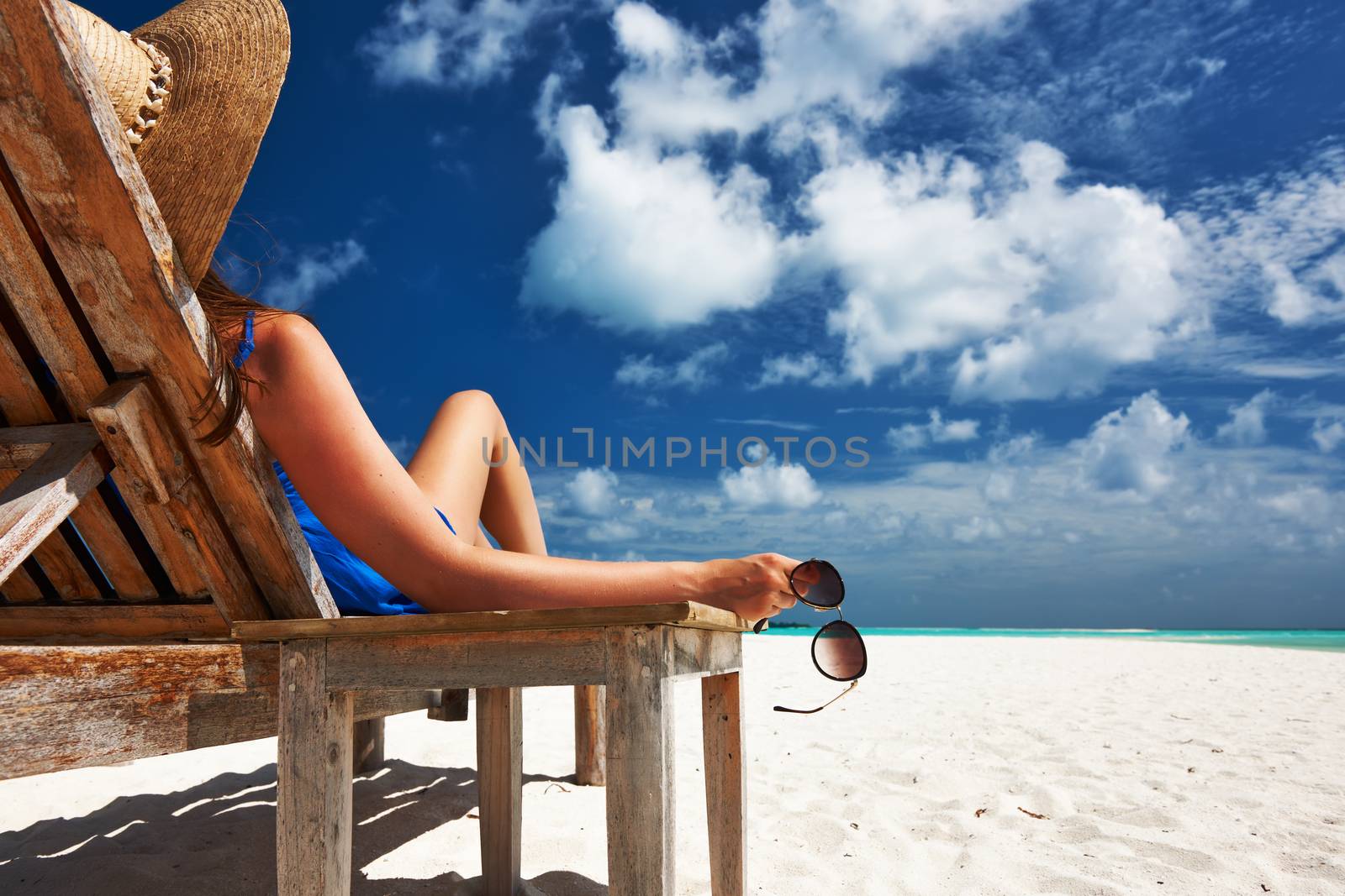 Woman at beautiful beach holding sunglasses