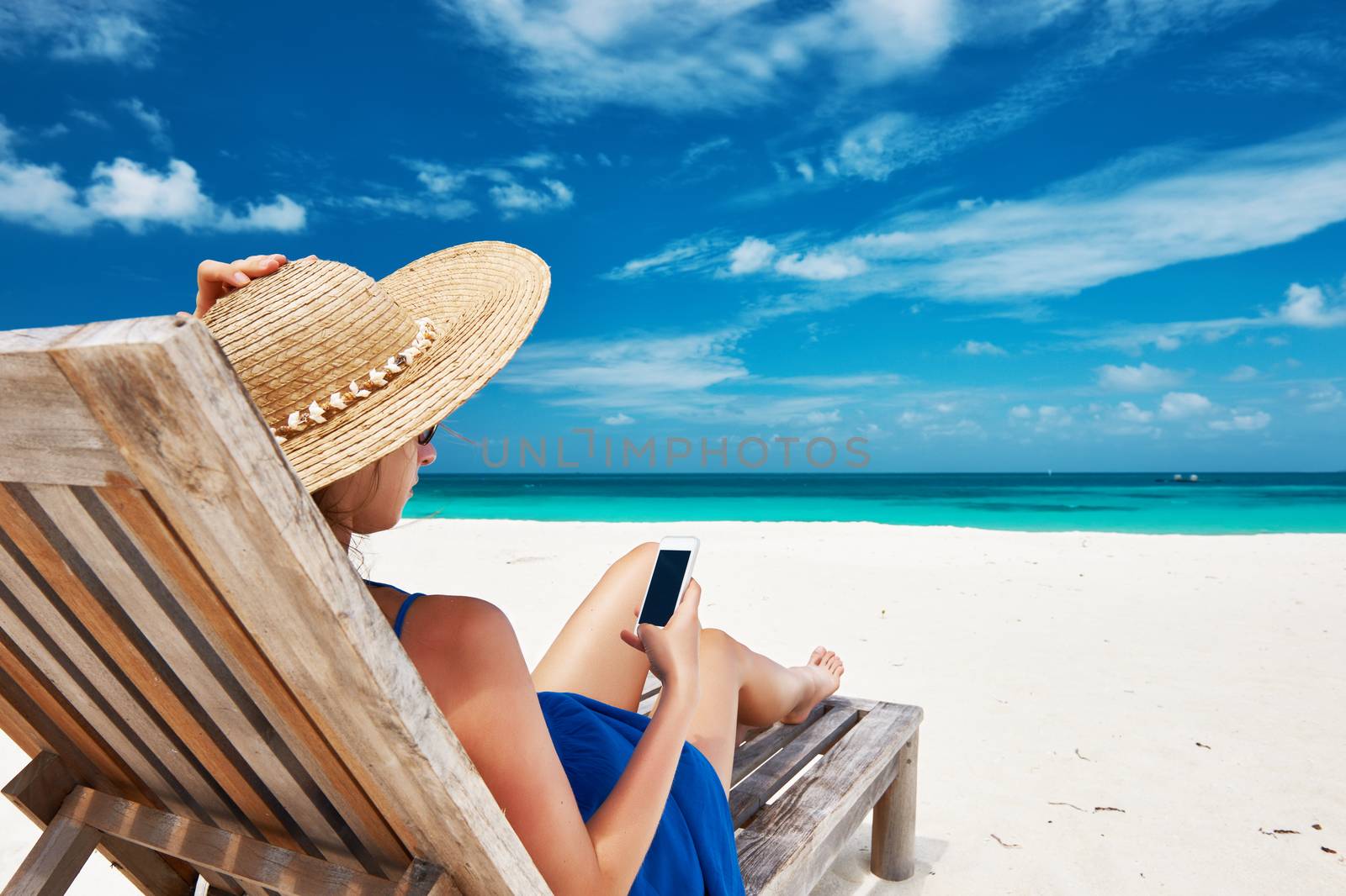 Young woman in hat with mobile phone at the beach