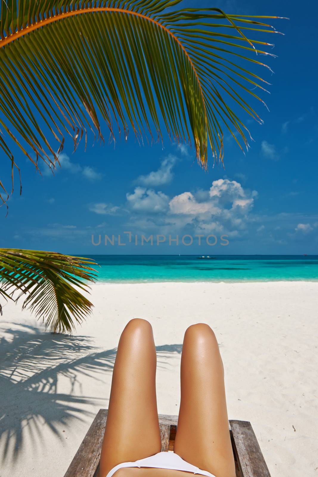 Woman at beautiful beach lying on chaise lounge