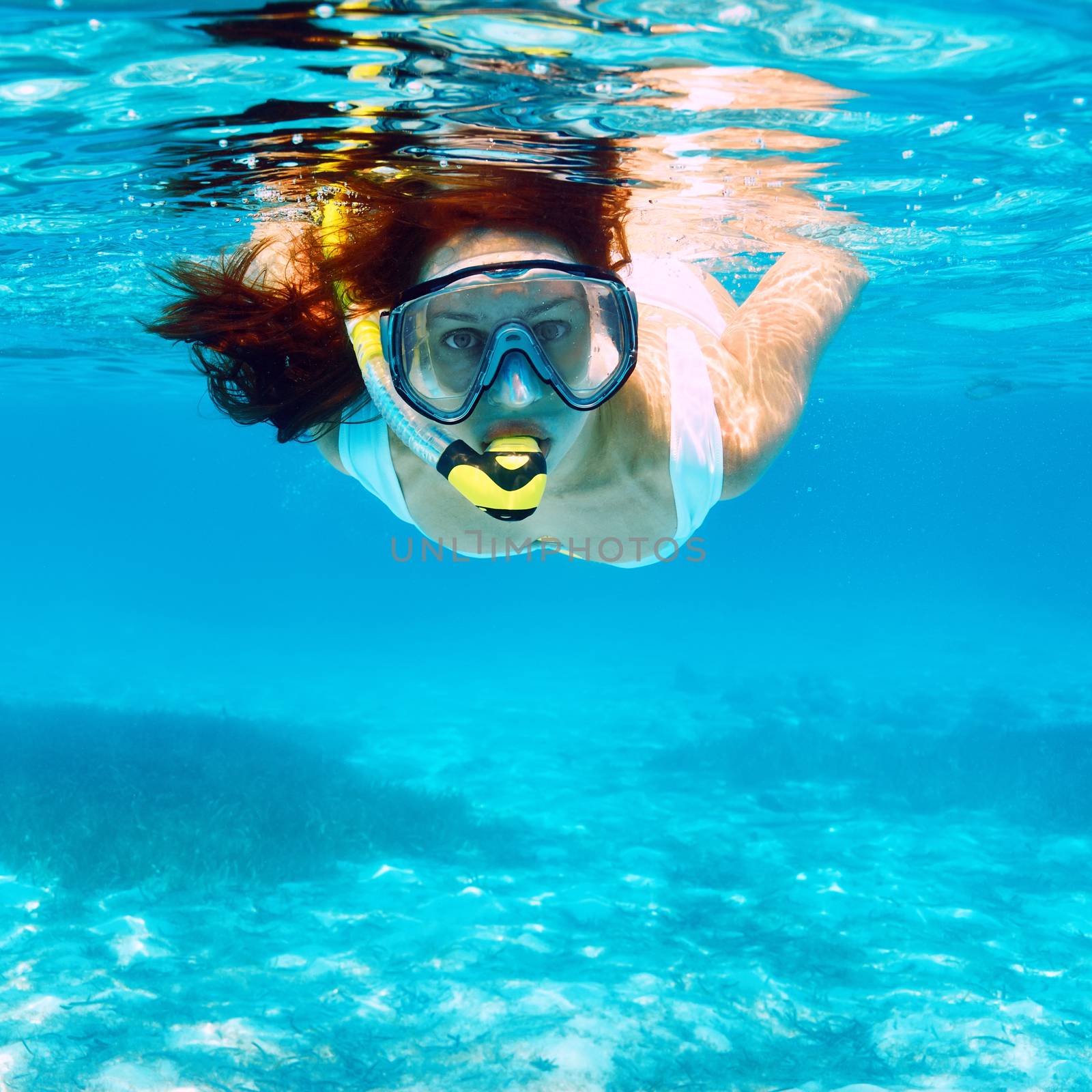 Woman with mask snorkeling in clear water 