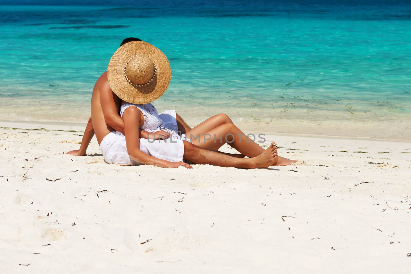 Couple in white relax on a tropical beach at Maldives