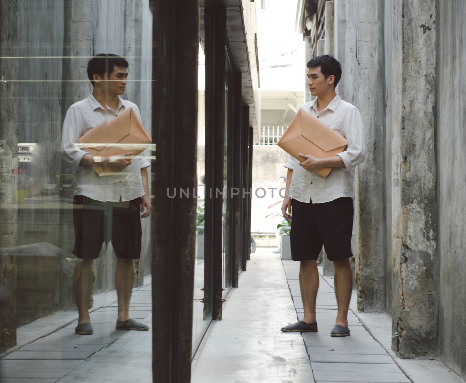 Attractive man with leather bag on grunge concrete background by siraanamwong