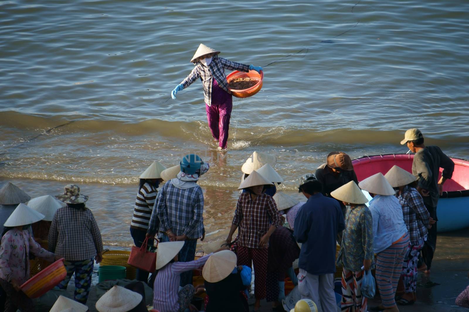 PHAN THIET, VIET NAM- FEB 3: Crowd of people make deal with fish at seashore in Phan Thiet, Viet Nam on Feb 3, 2013