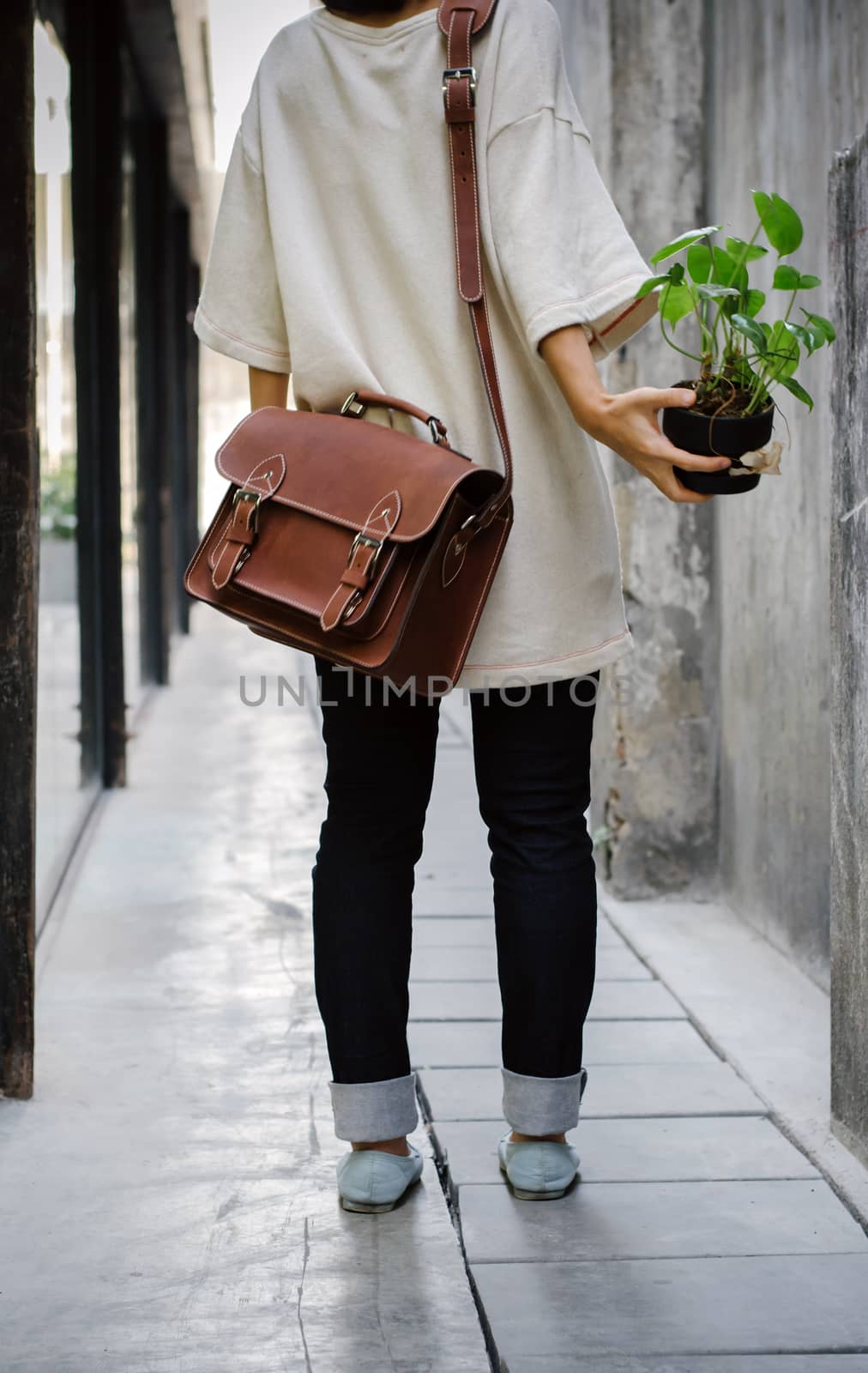 Woman with brown leather bag and hold the plant