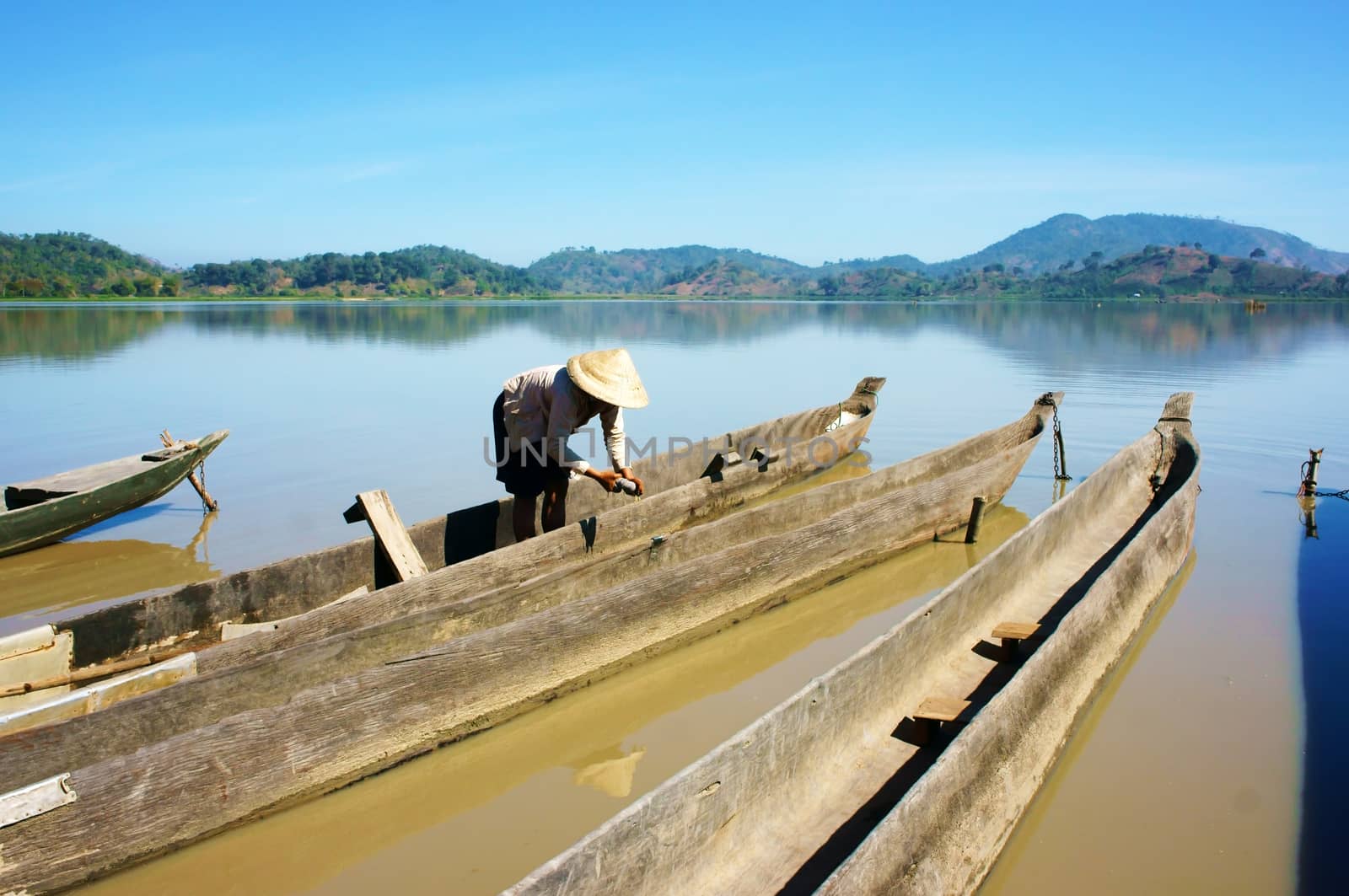 BUON ME THUOT, VIET NAM- FEBRUARY 18: People clean dug out canoe (boat) to transport  for travel in Buon Me Thuot, VietNam on February 18, 2013