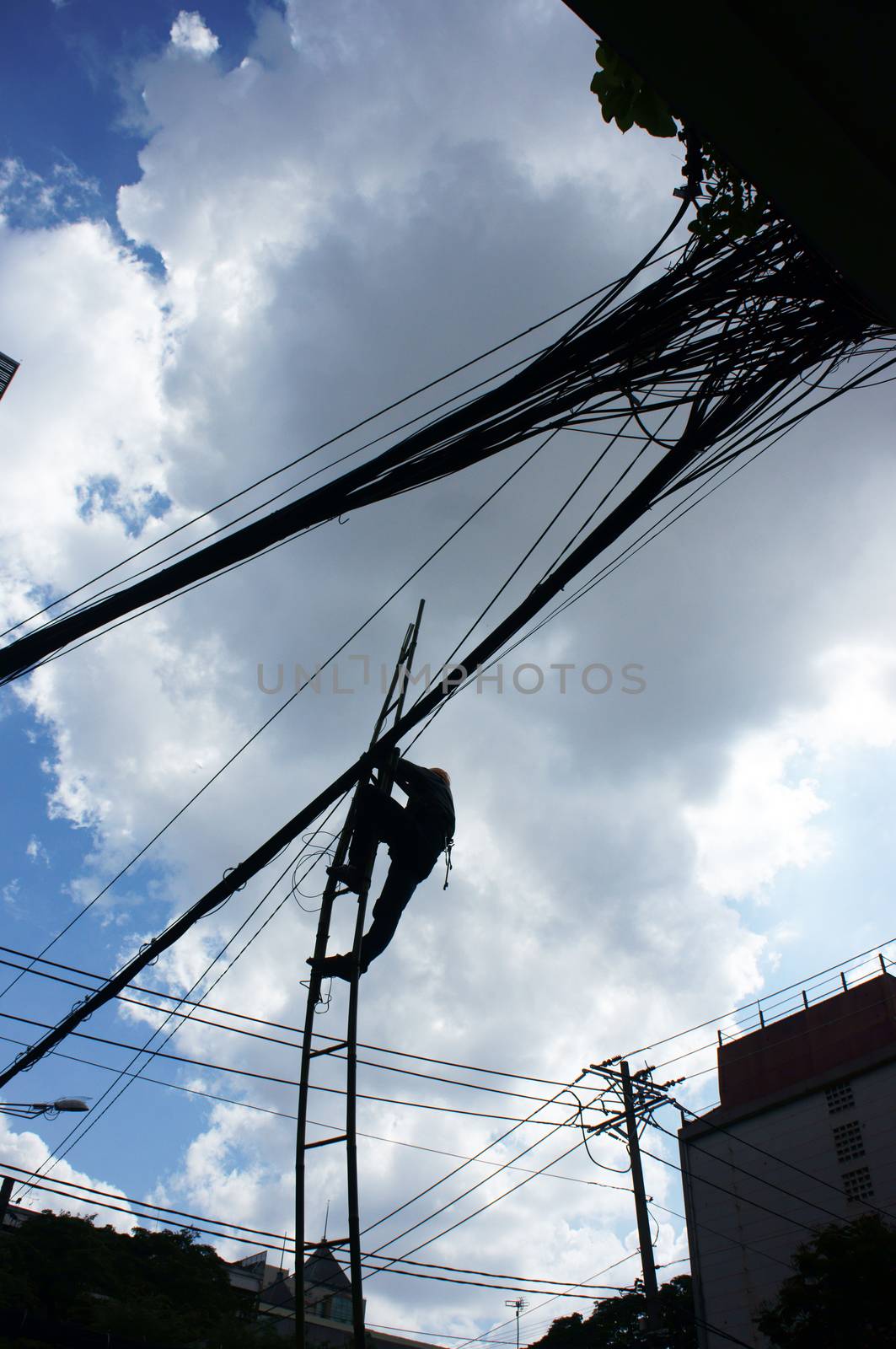 Electrician working among electric wire network in the blue sky as spider