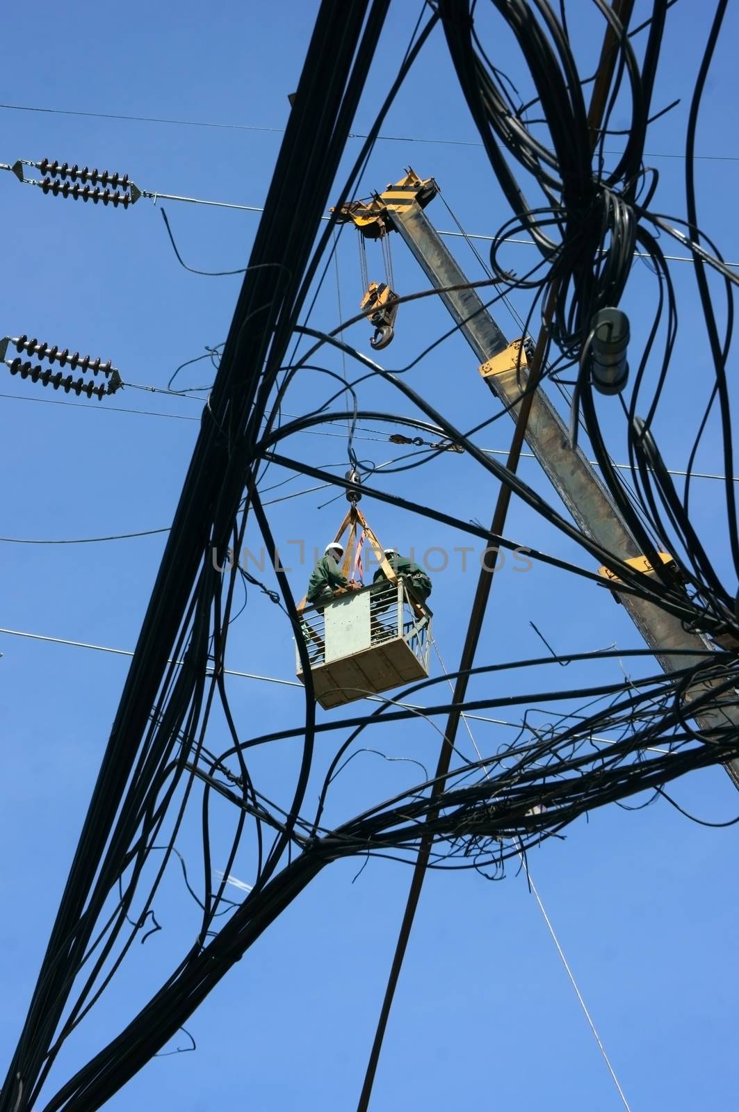 SAI GON, VIET NAM- APRIL 29: Electrician working among electric wire network in the blue sky as spider in Sai Gon, VN on April 29, 2013