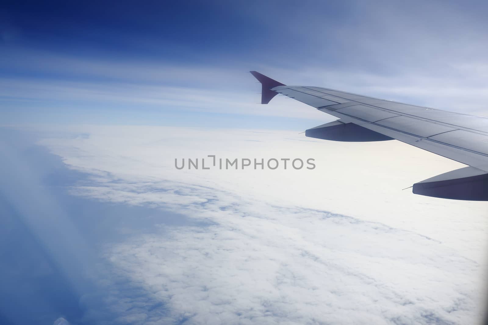 Wing of an airplane flying above the clouds.  by rufous