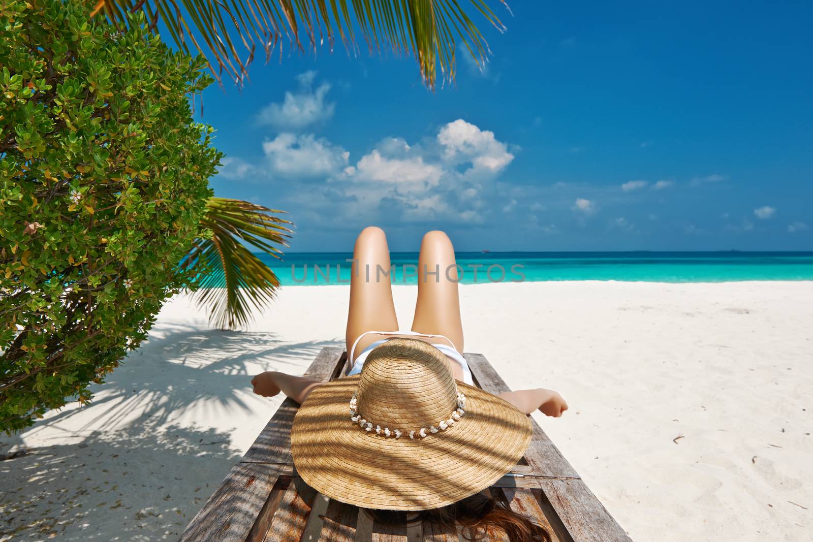 Woman at beautiful beach lying on chaise lounge