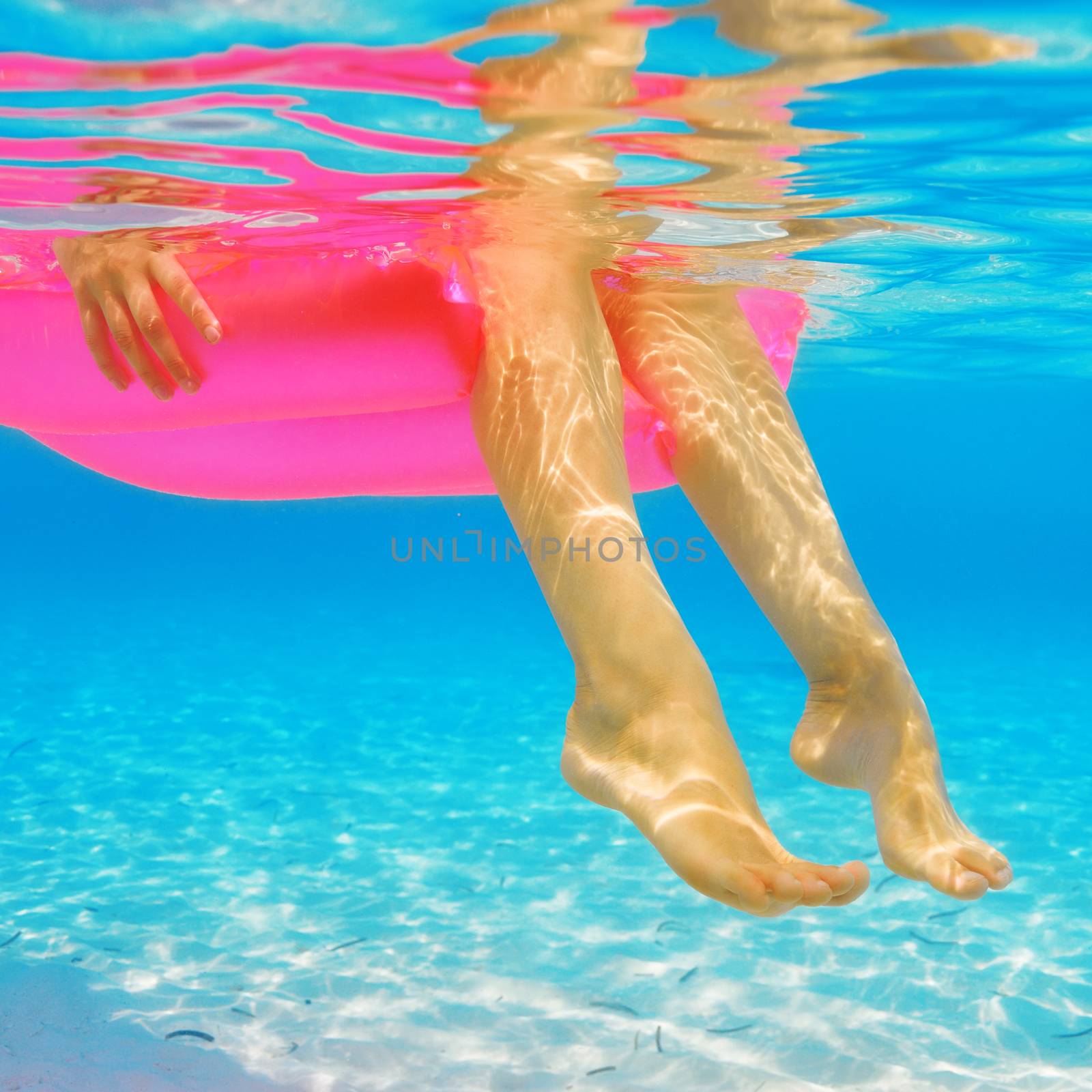 Woman relaxing on inflatable mattress, view from underwater by haveseen