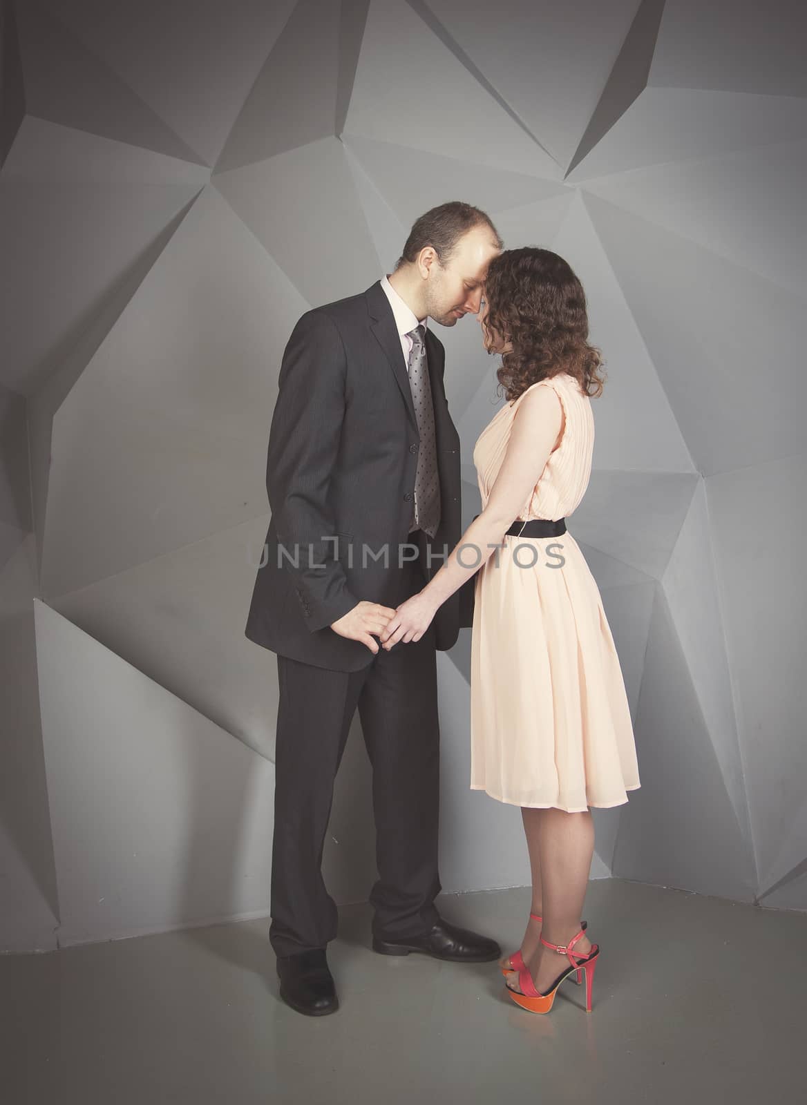 young man gently embraces a girl on a grey background