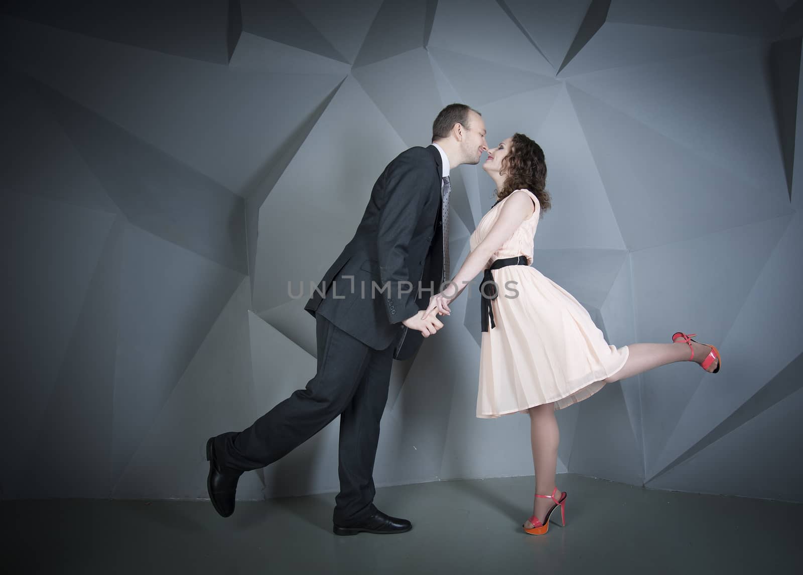 young man gently embraces a girl on a grey background