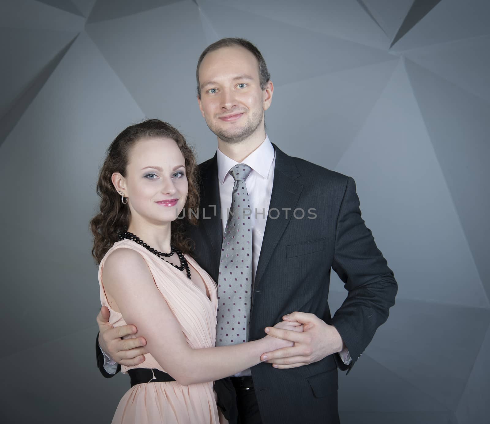 young man gently embraces a girl on a grey background