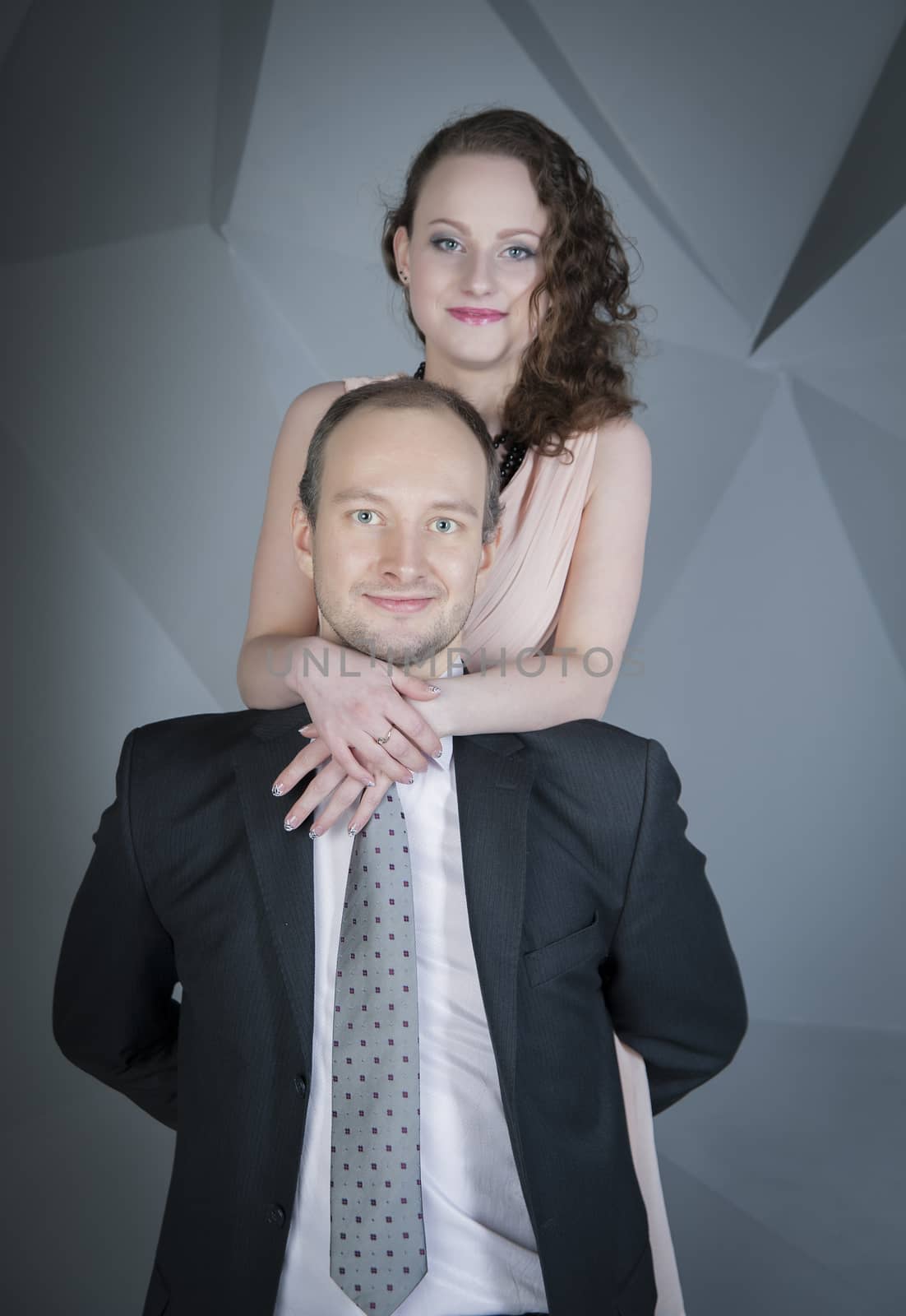 young man gently embraces a girl on a grey background