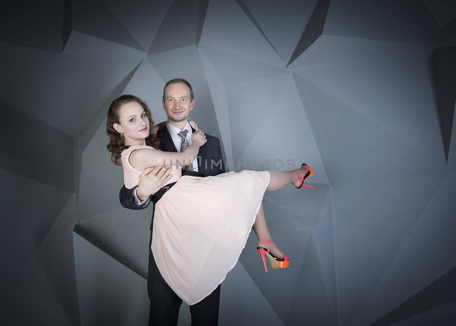 young man gently embraces a girl on a grey background