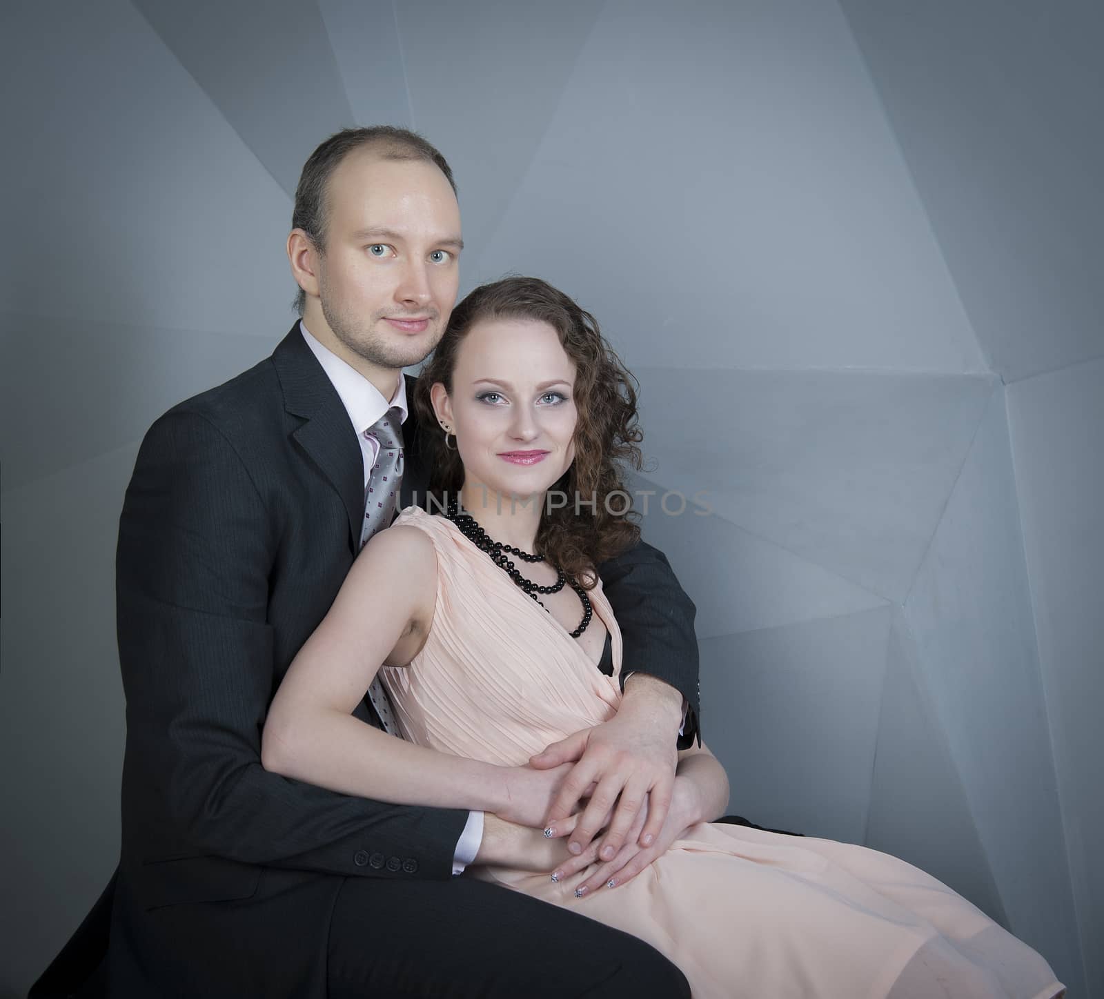 young man gently embraces a girl on a grey background