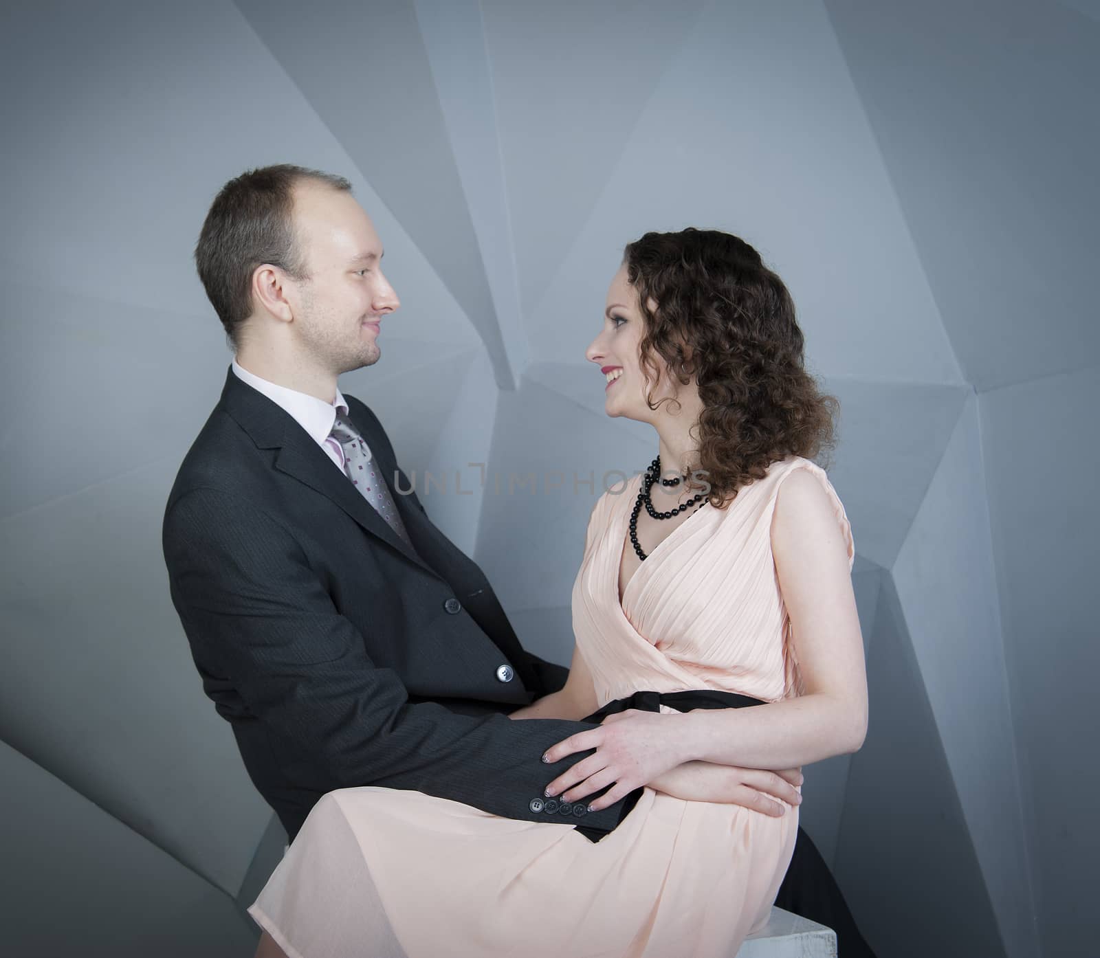 young man gently embraces a girl on a grey background