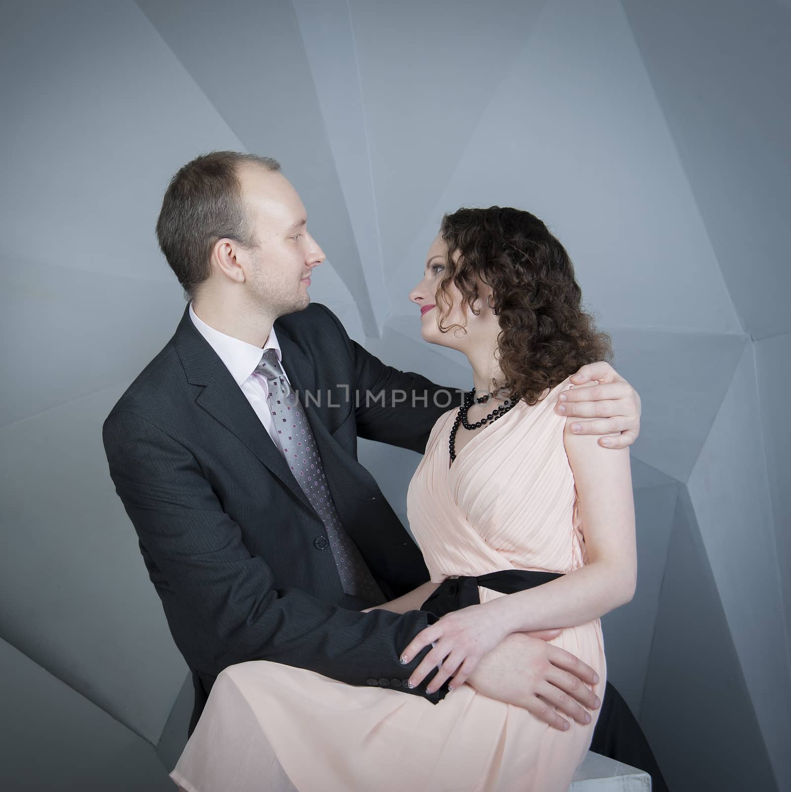 young man gently embraces a girl on a grey background