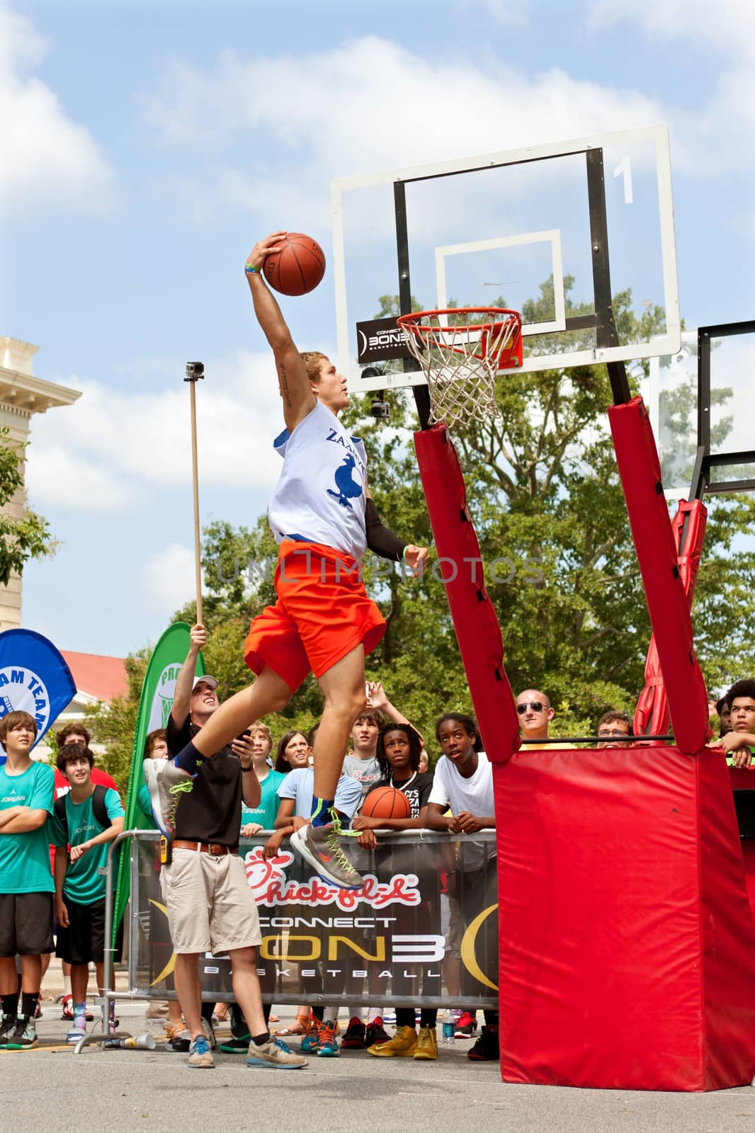 Athens, GA, USA - August 24, 2013:  A young man elevates above the rim to dunk a basketball in the slam dunk competition of a 3-on-3 basketball tournament held in the streets of downtown Athens.