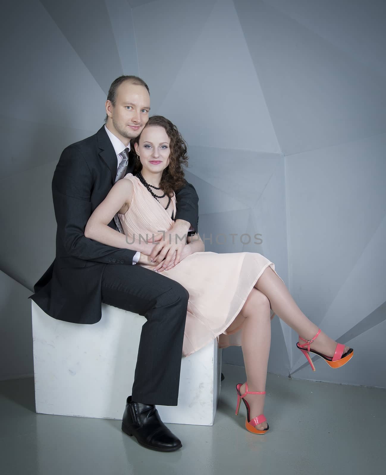 young man gently embraces a girl on a grey background