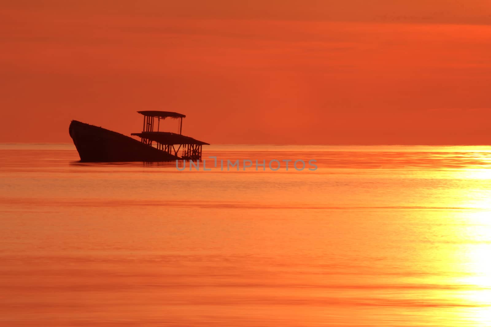 Silhouette abandon fisherman boath over sunset sky