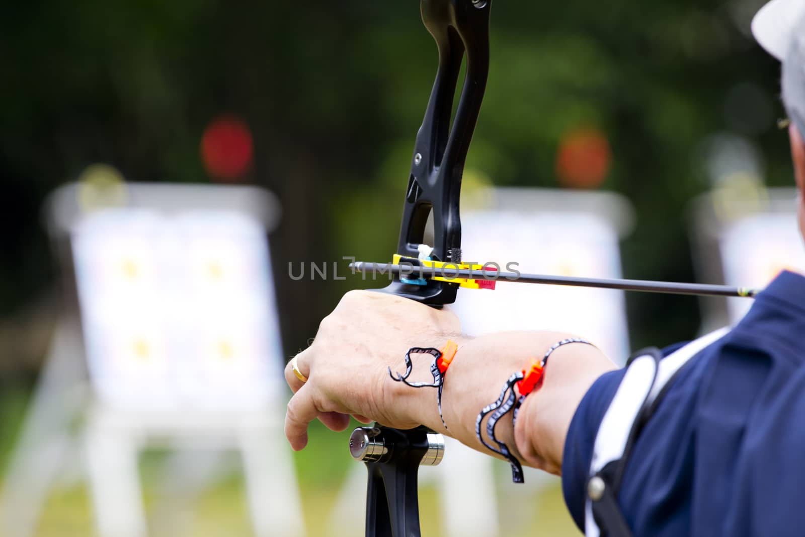 archer holds his bow aiming at target.