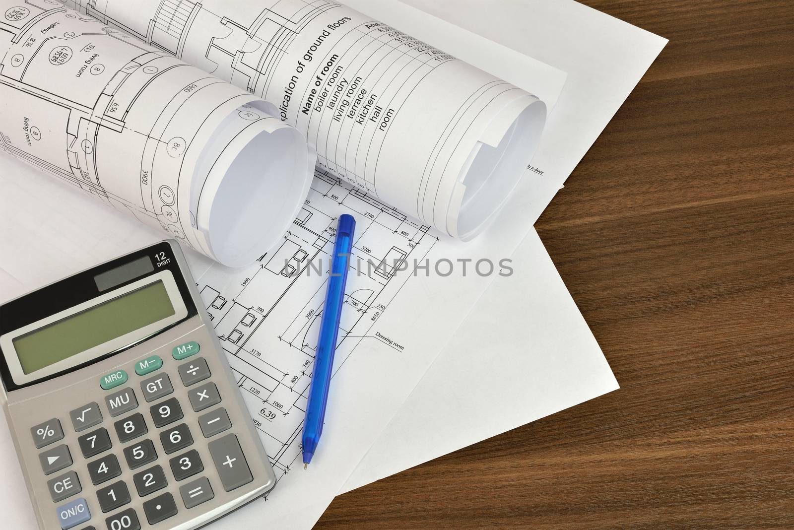 Construction drawings, calculator and pen on a wooden surface. Workplace architect