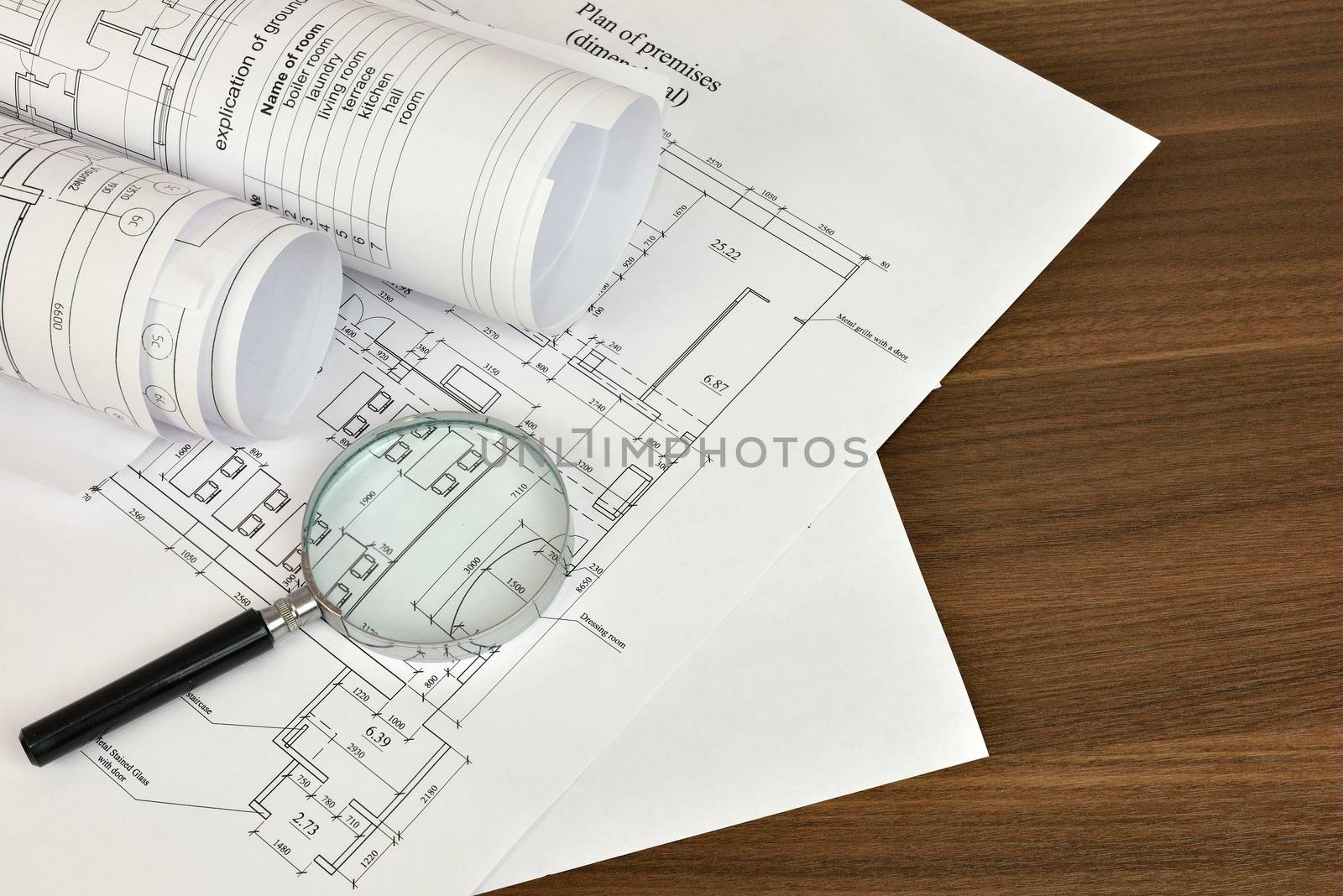 Construction drawings and magnifying glass on a wooden surface. Workplace architect