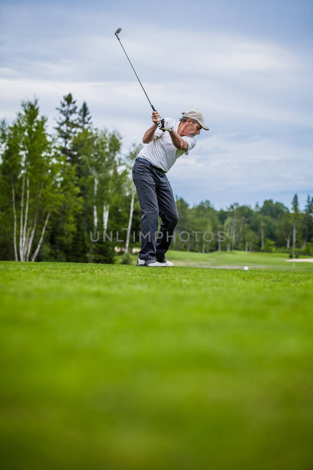 Mature Golfer on a Golf Course Taking a Swing on the Start (with room for your text)