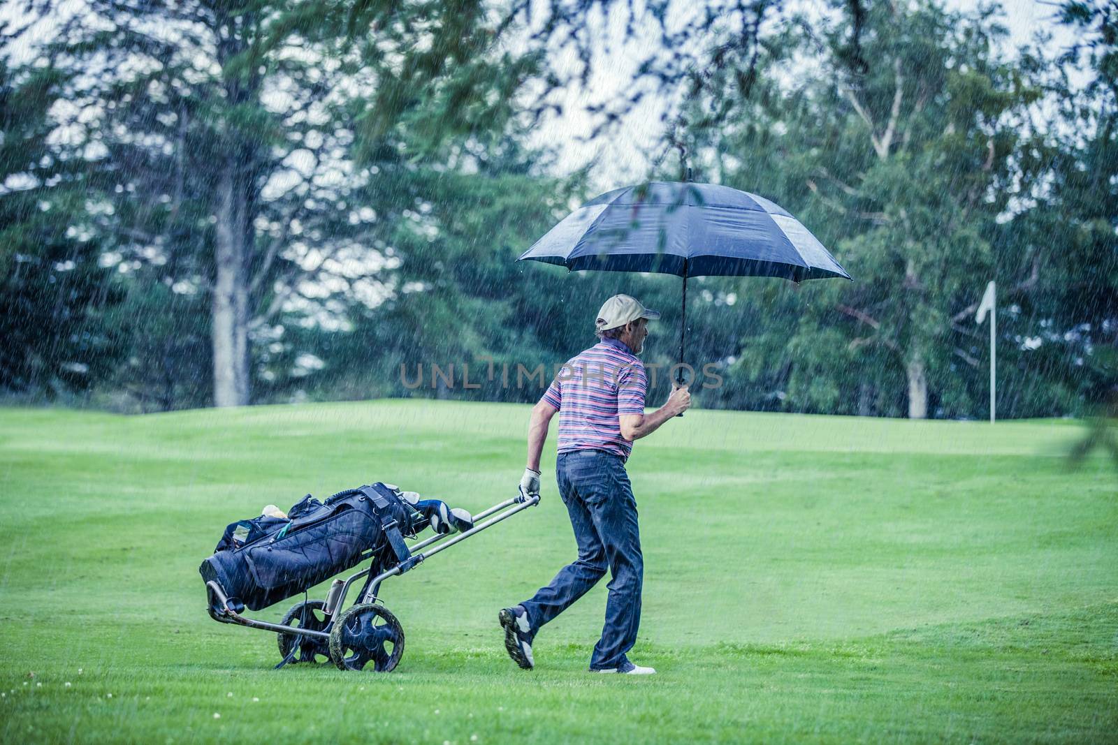 Golfer on a Rainy Day Leaving the Golf Course by aetb